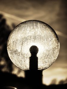 Schwarz/Weiß Foto einer Kugelförmigen Lampe die von hinten von der Sonne angestrahlt wird